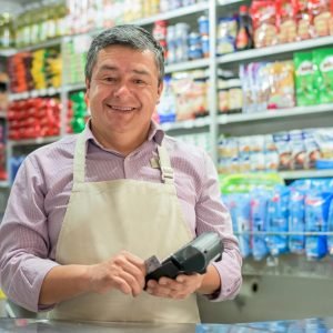 Propietario de negocio en una tienda local con un lector de tarjetas de crédito, utilizando conceptos de tecnología